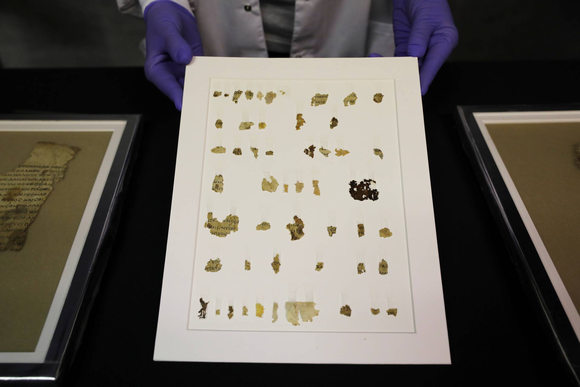 An employee shows recently-discovered scroll fragments of an ancient biblical text at Israel Antiquities Authority laboratories in Jerusalem