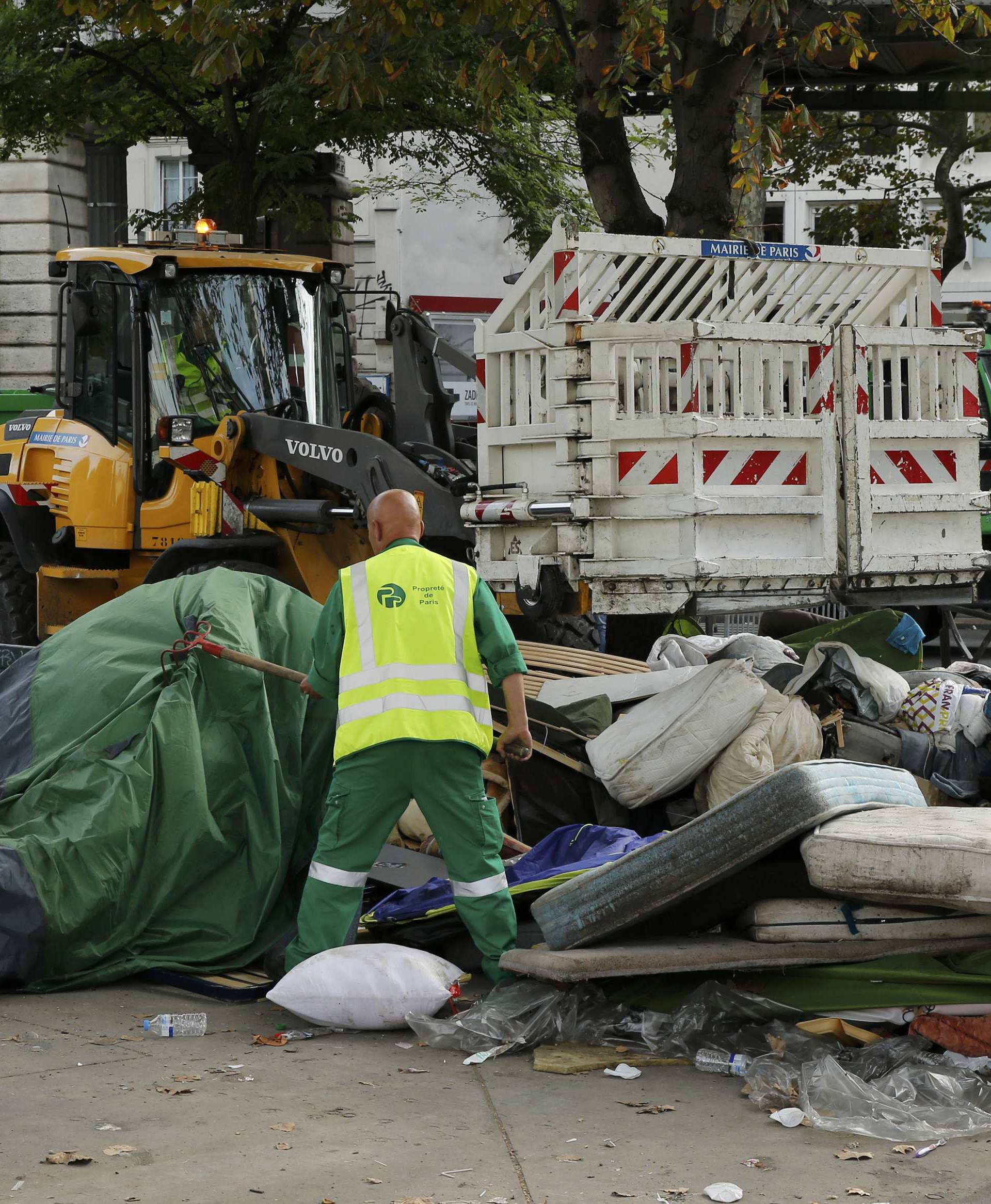 City workers remove tents and mattresses from an evacuated makeshift migrant camp near the metro stations of Jaures and Stalingrad in Paris