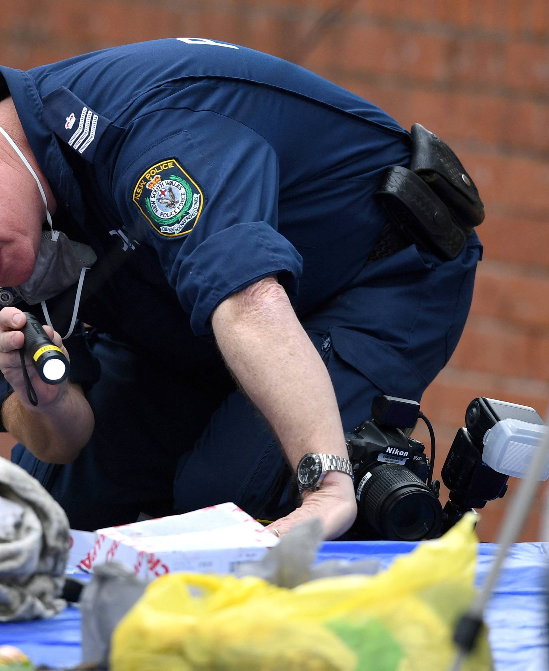 An Australian police officer searches items seized from a property during a raid in the Sydney suburb of Lakemba