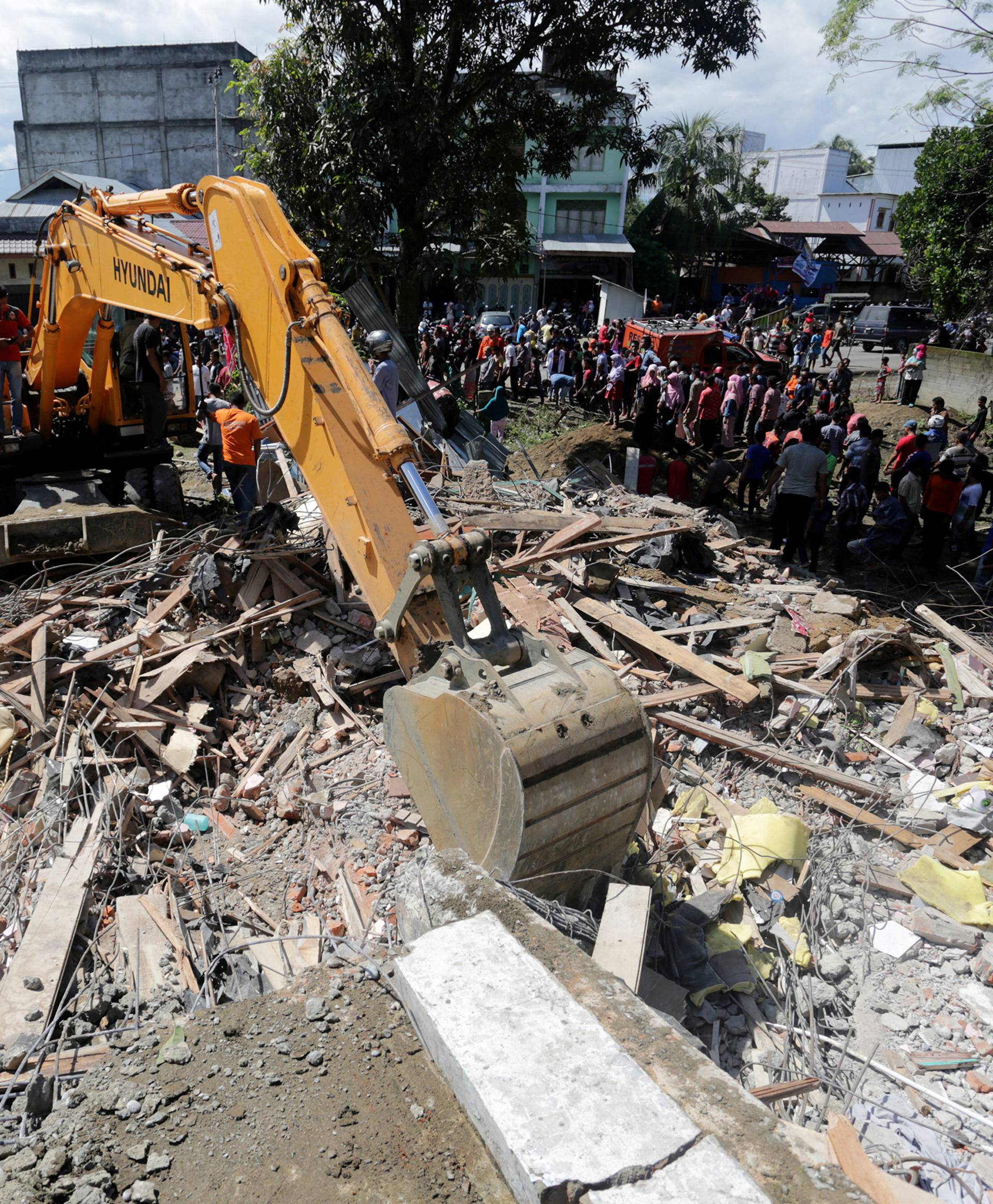 Rescue workers use heavy equipment to search for victims in a collapsed building following an earthquake in Lueng Putu, Pidie Jaya in the northern province of Aceh, Indonesia