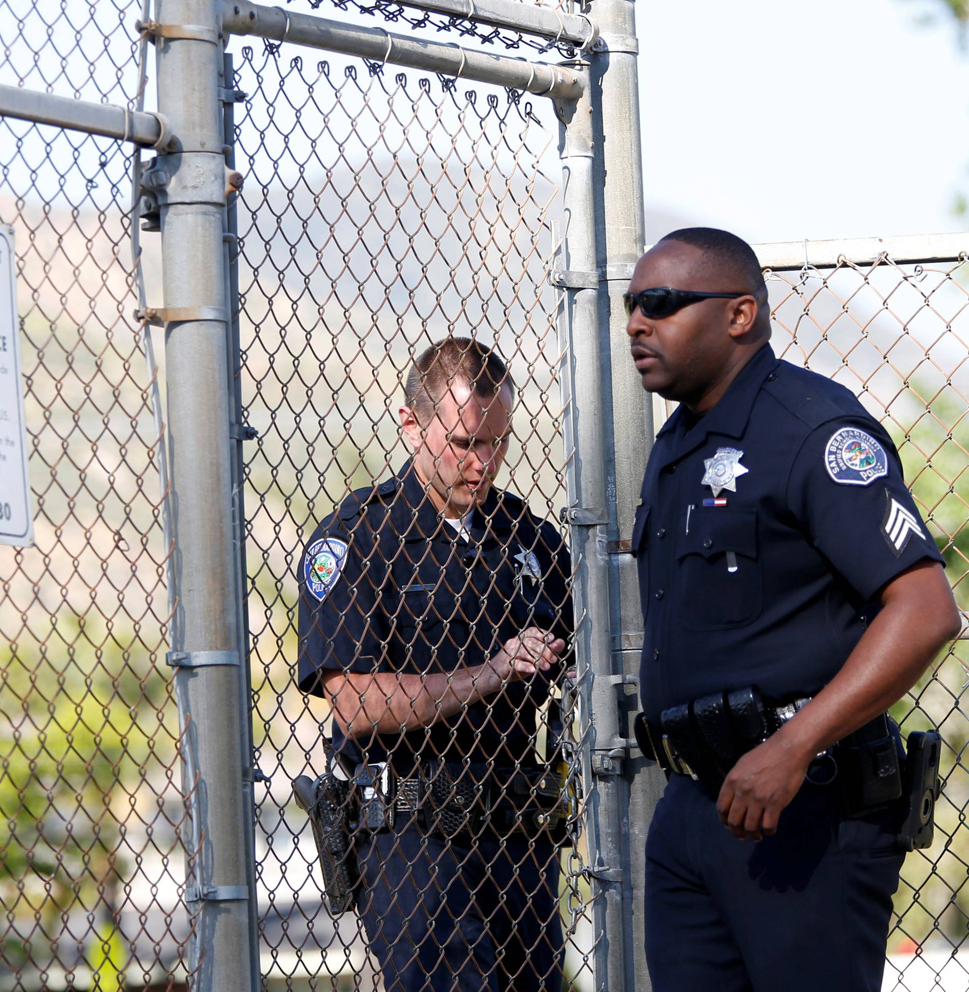 Police officers lock a gate after a shooting at North Park Elementary School in San Bernardino