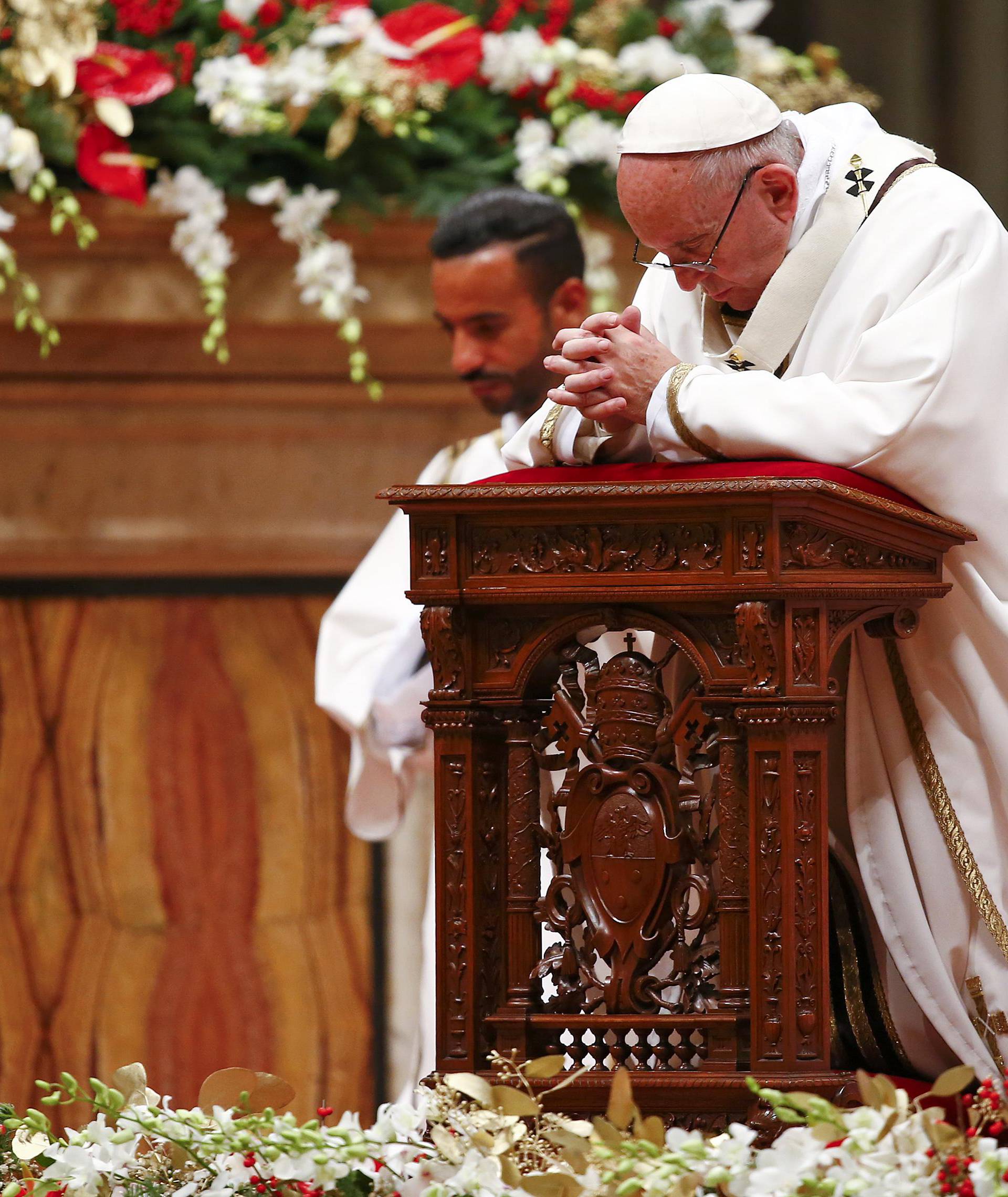 Pope Francis kneels as he leads the Christmas night Mass in Saint Peter's Basilica at the Vatican