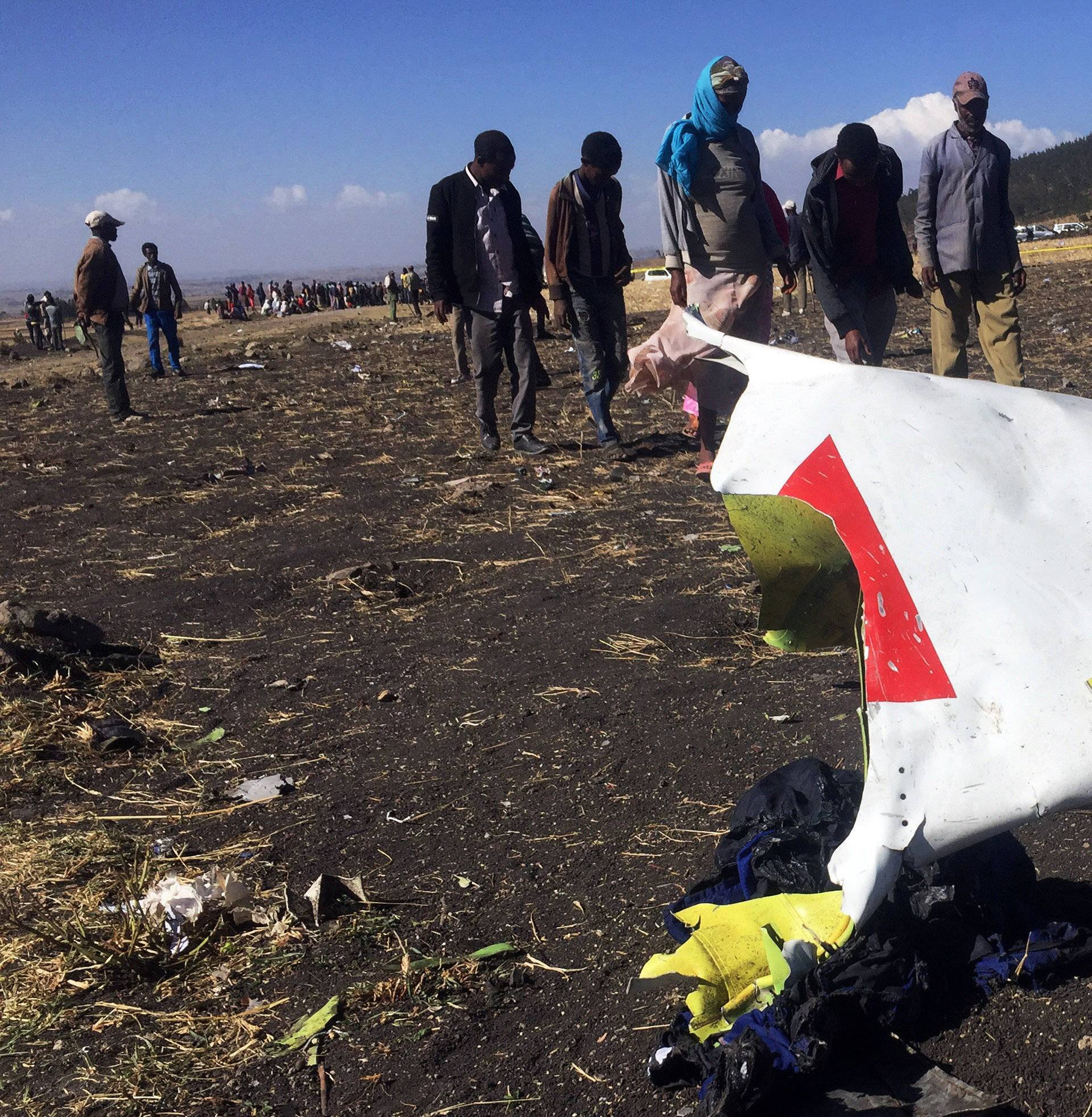 People walk past a part of the wreckage at the scene of the Ethiopian Airlines Flight ET 302 plane crash, near the town of Bishoftu, southeast of Addis Ababa