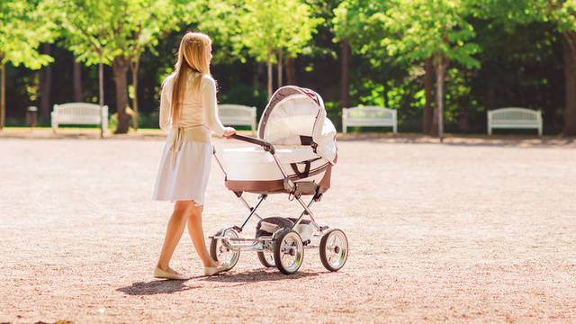 happy mother with stroller in park