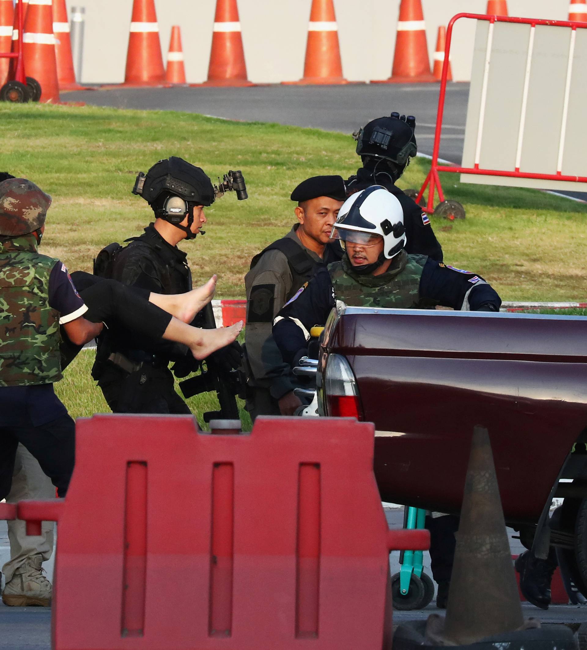 A woman who fainted is assisted by Thai security forces evacuating people stranded inside the Terminal 21 shopping mall following a gun battle, to try to stop a soldier on a rampage after a mass shooting, Nakhon Ratchasima