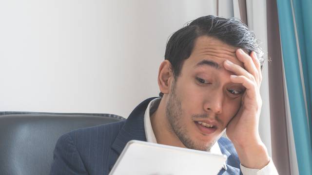 Business man is shock looking at tablet computer