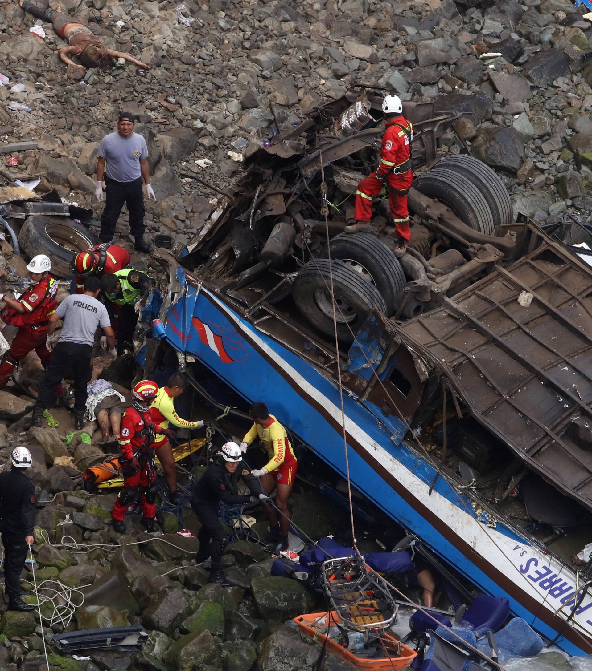 Rescue workers work at the scene after a bus crashed with a truck and careened off a cliff along a sharply curving highway north of Lima