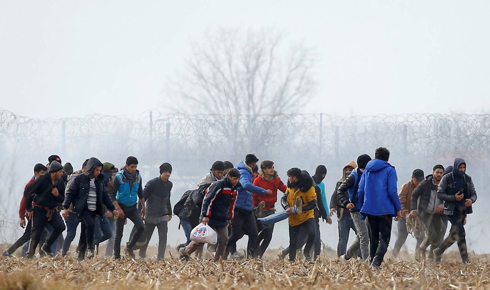 Migrants carry an injured man near the Turkey's Pazarkule border crossing with Greece's Kastanies, near Edirne