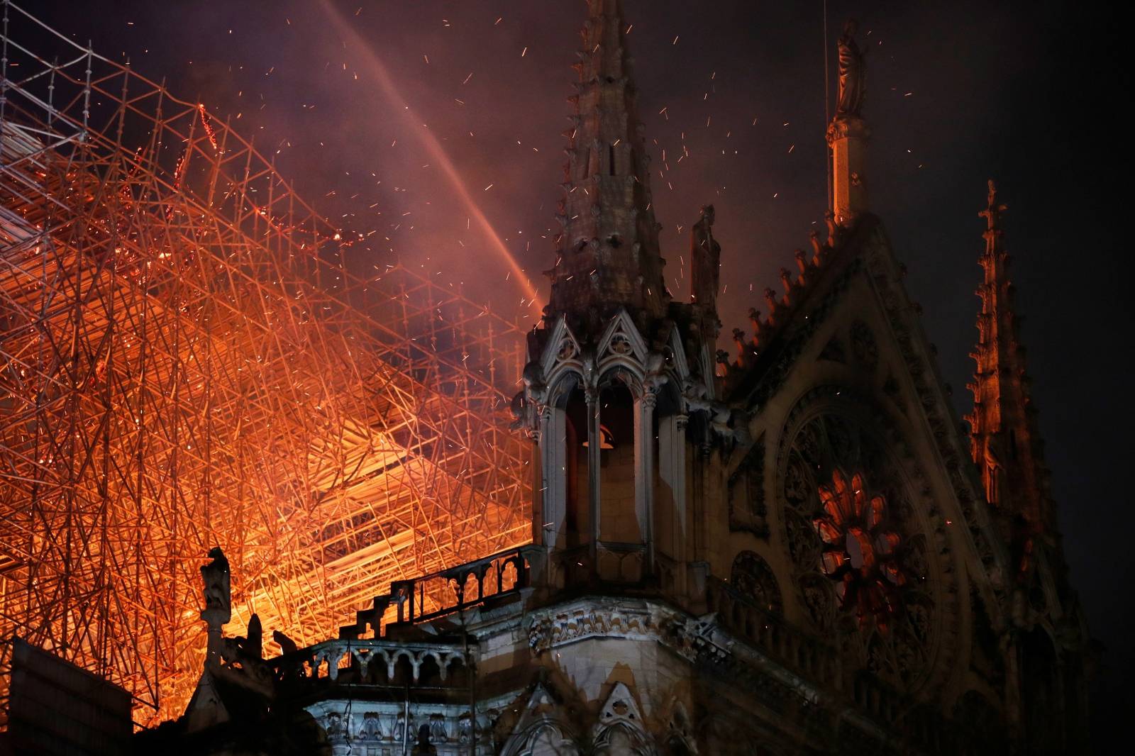 Sparks fill the air as Paris Fire brigade members spray water to extinguish flames as the Notre Dame Cathedral burns in Paris