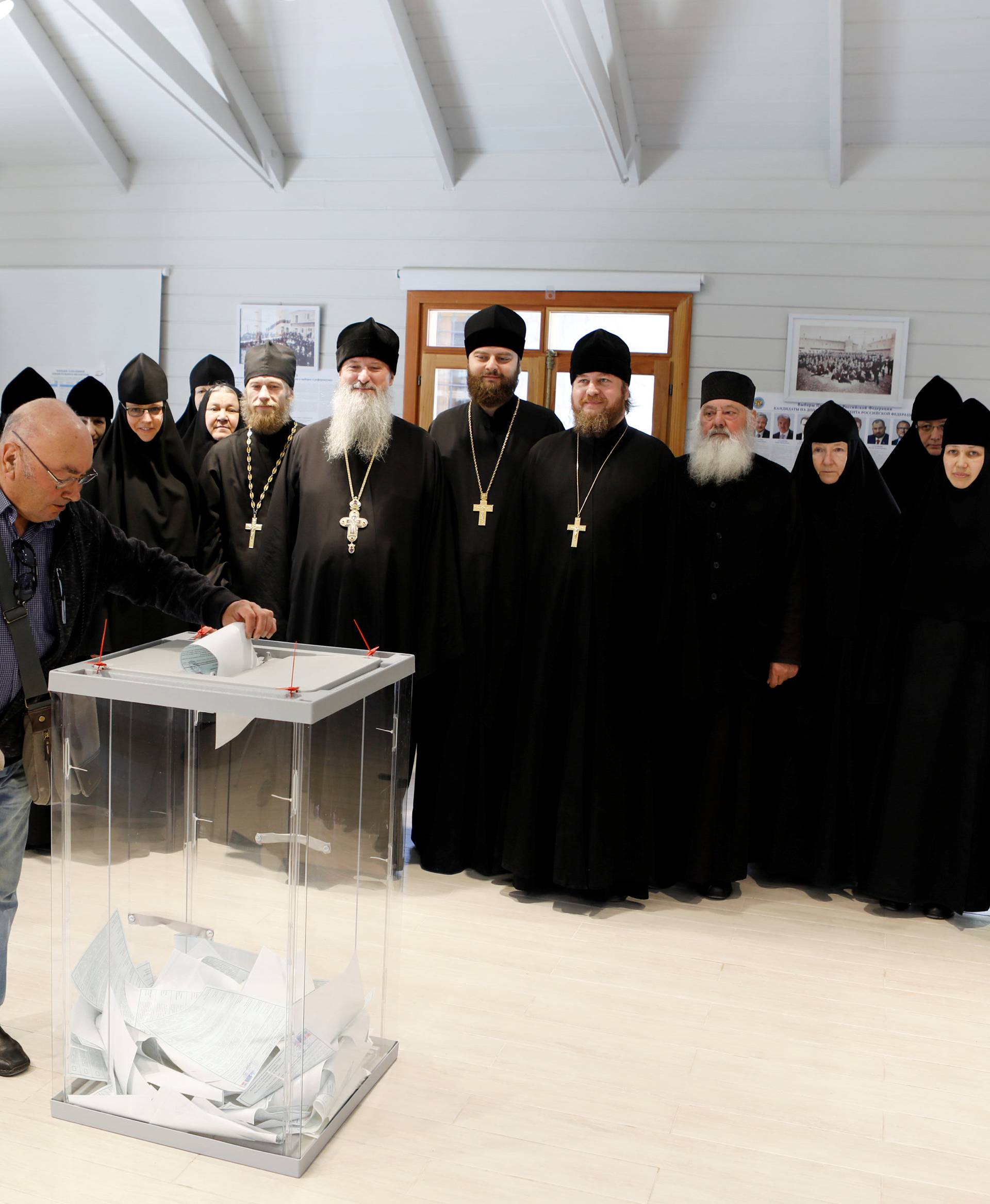Russian clergymen and nuns pose for a group photo as a Russian citizen casts his ballot for Russia's presidential election in a polling station in Jerusalem