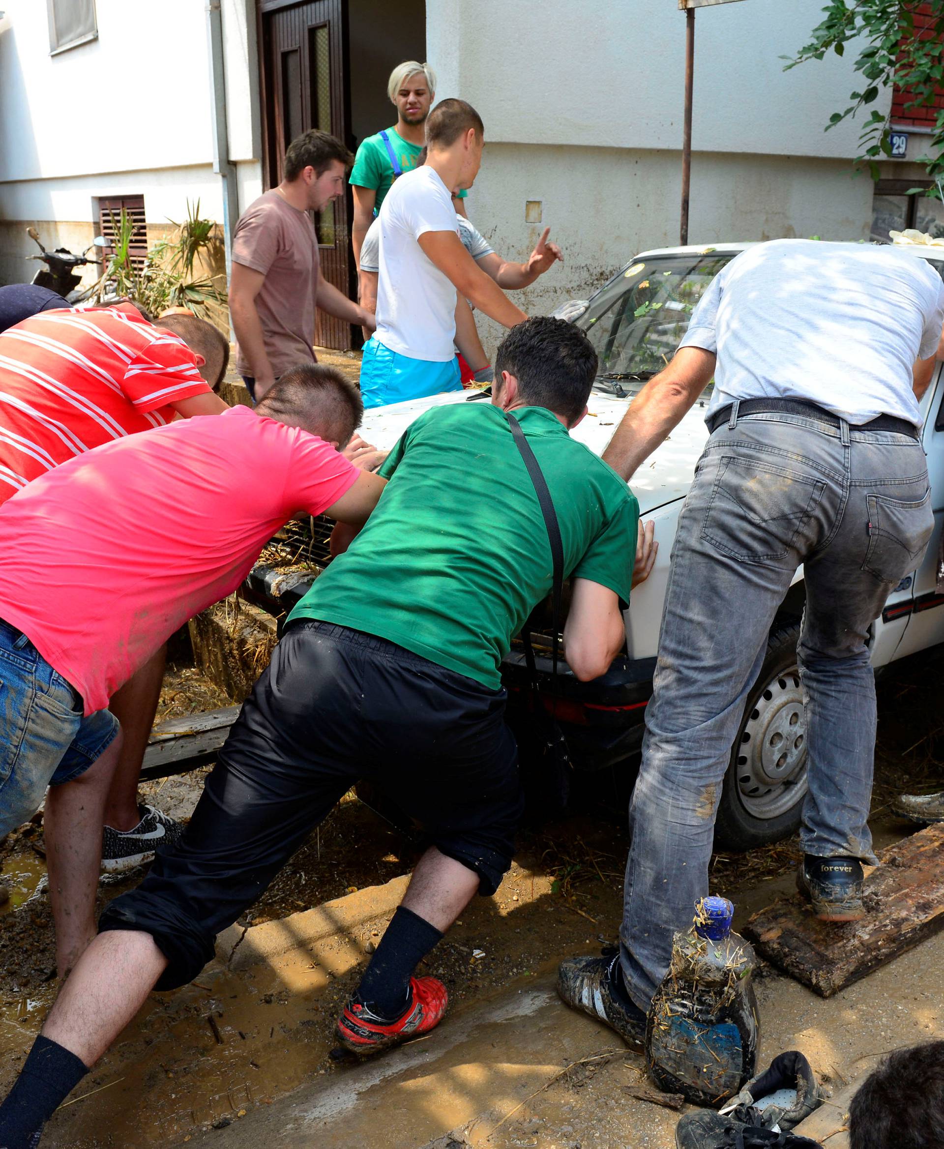 People clean up wrecked car after heavy floods in Cento near Skopje