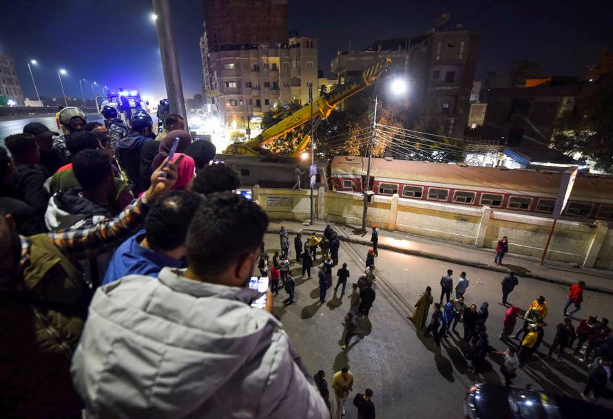 People watch as they gather on a bridge above the scene of a train crash in the city of Qalyub in Al Qalyubia Governorate, north of Cairo