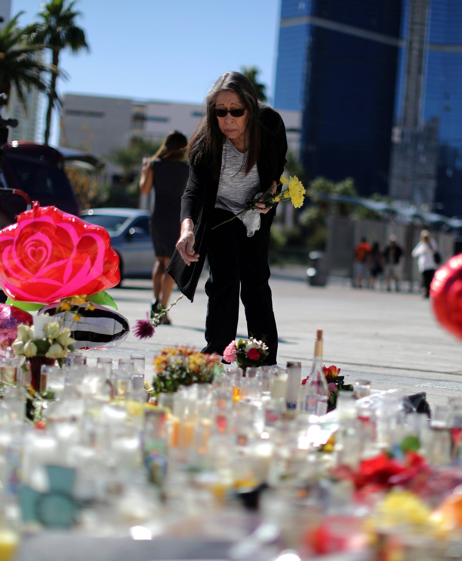 A woman leaves flowers at a makeshift memorial on the Las Vegas Strip for victims of the Route 91 music festival mass shooting next to the Mandalay Bay Resort and Casino in Las Vegas