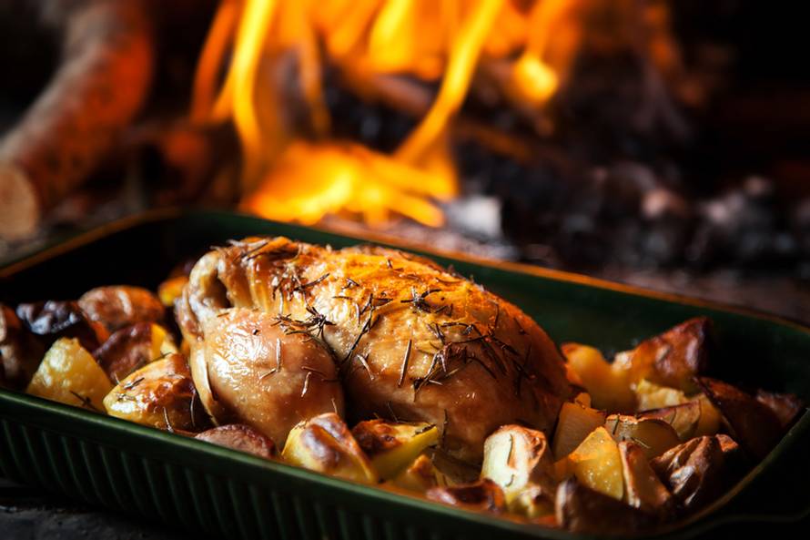 Roast chicken with potatoes with fiery background.