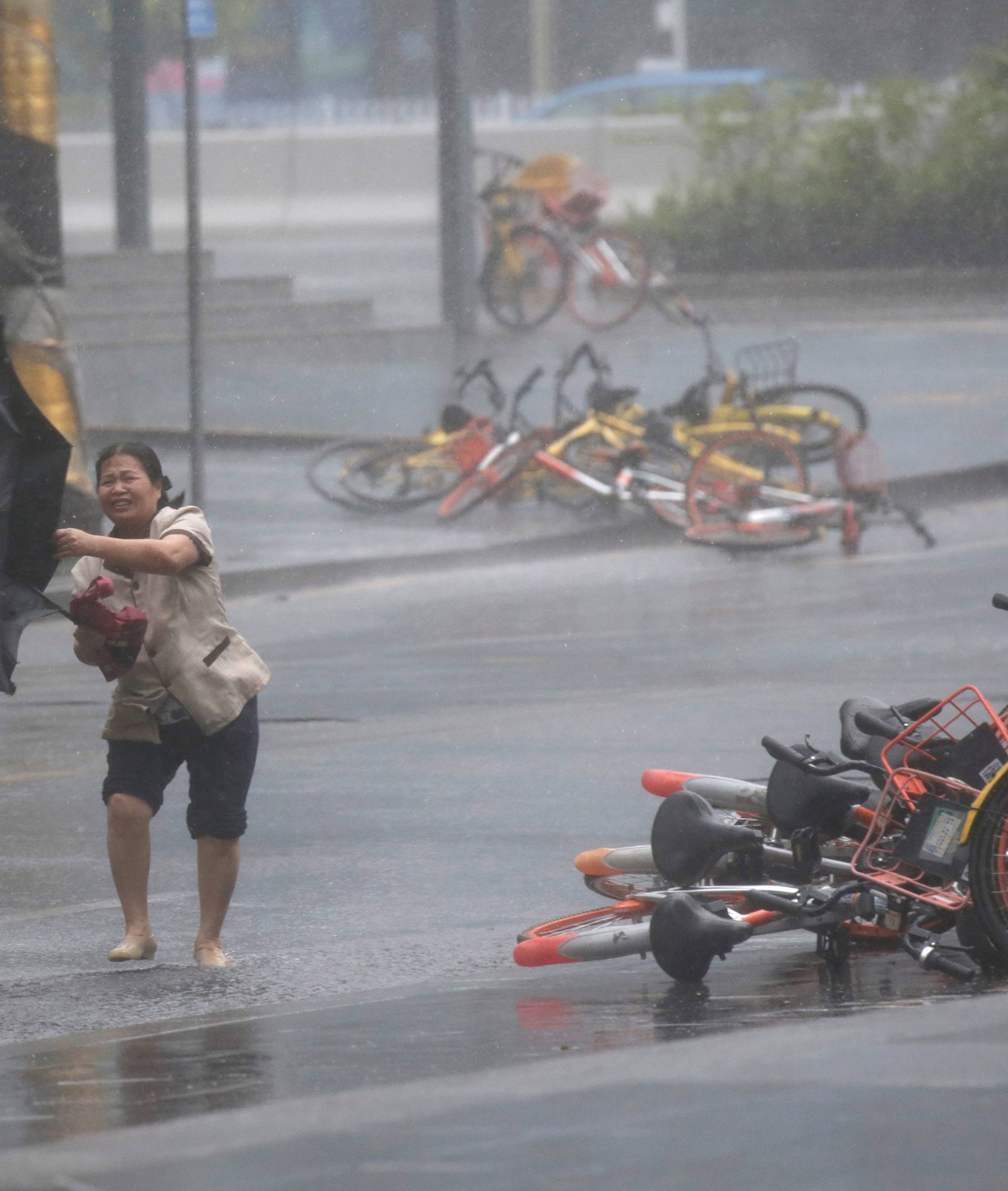 A woman holding an umbrella walks in the rainstorm as Typhoon Mangkhut approaches in Shenzhen