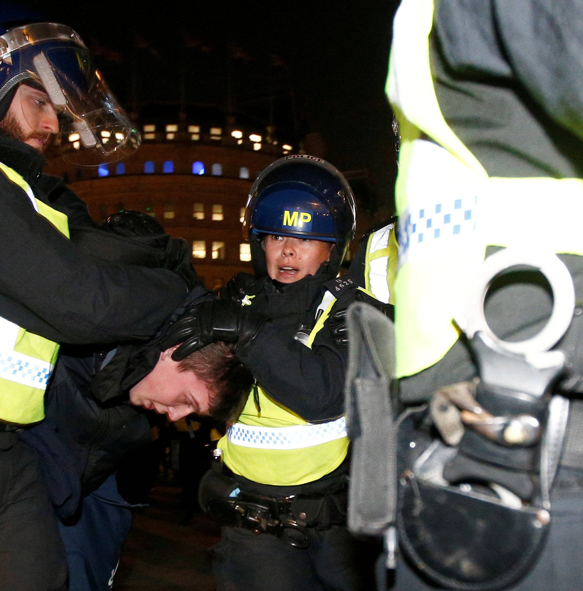 Police officers apprehend a protester during the "Million Mask March" in London