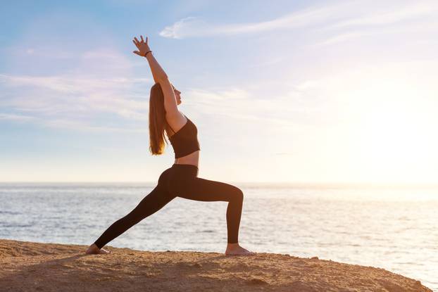 Young woman practicing yoga asana pose in the morning at the sea