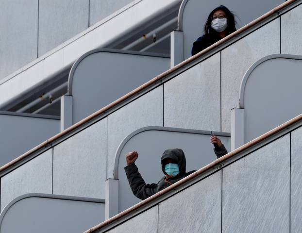 A passenger reacts as the cruise ship Diamond Princess, where 10 people on the ship had tested positive for coronavirus yesterday, arrives at Daikoku Pier Cruise Terminal in Yokohama