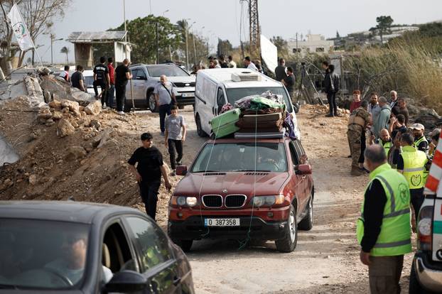 Displaced people cross the bridge linking southern Lebanon to the rest of the country, which was hit earlier in an Israeli strike, in Qasmiyeh