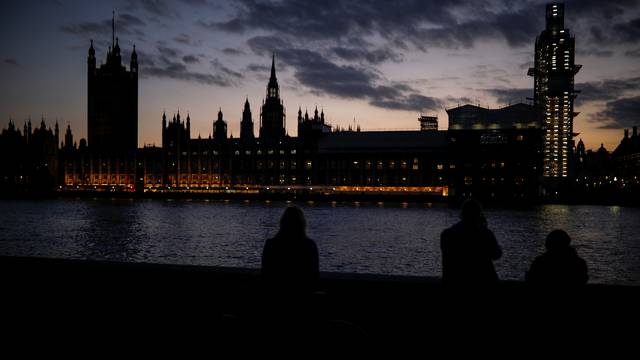People enjoy the view on the south bank of the River Thames, opposite the Houses of Parliament, in Westminster, central London
