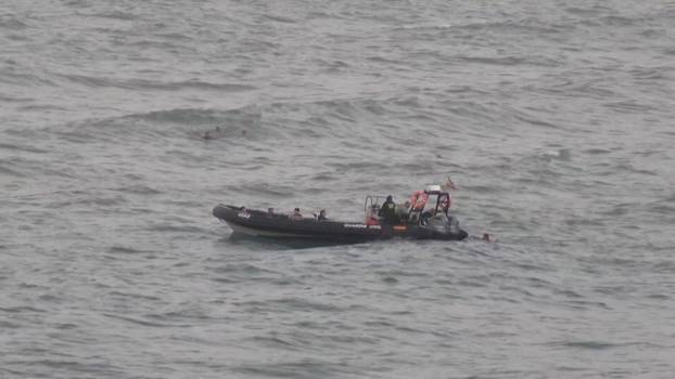 FILE PHOTO: A view shows migrants reaching a police boat, while other group of migrants swim in the background, in Ceuta