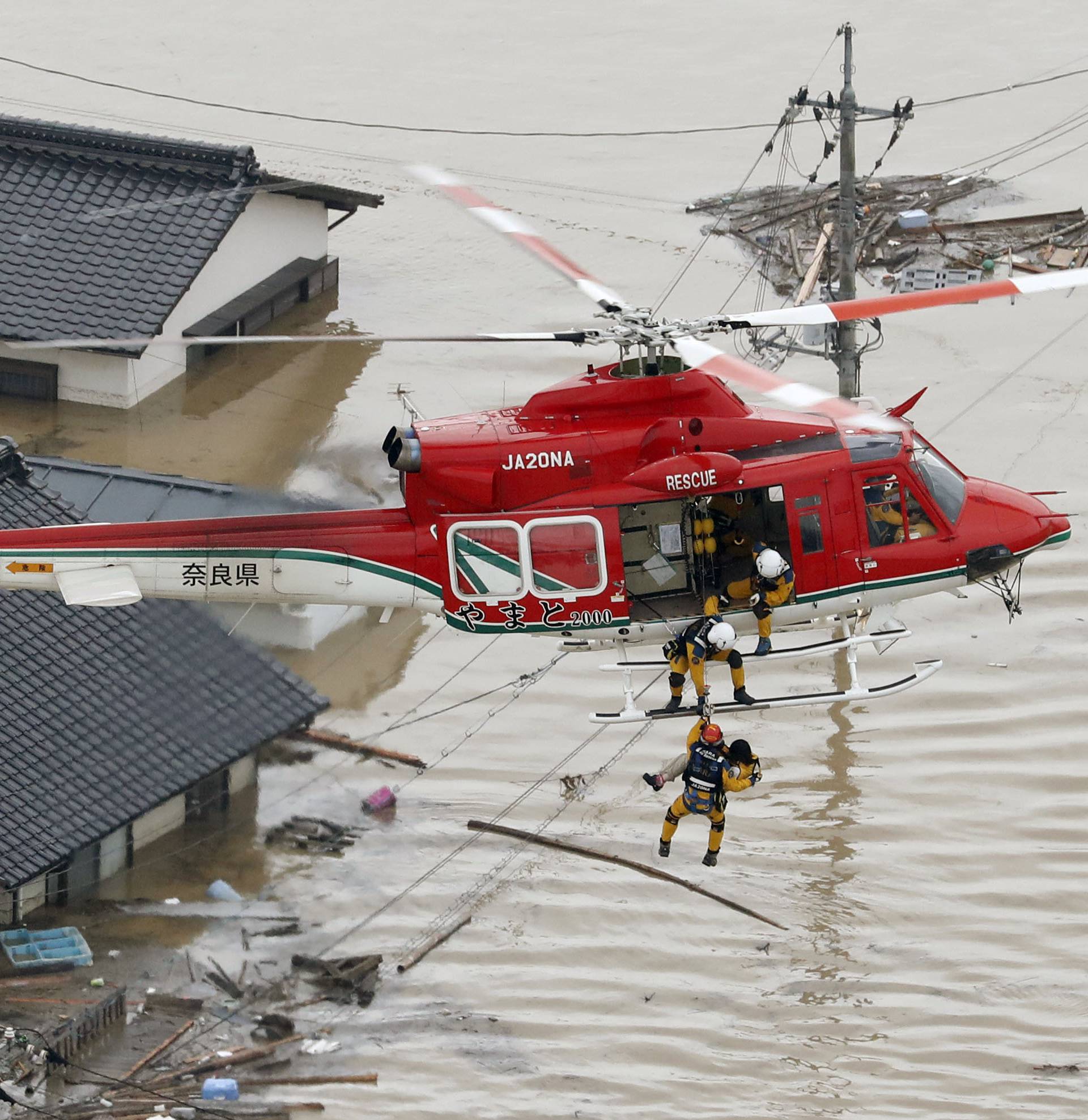 An aerial view shows a local resident being rescued from a submerged house by rescue workers using helicopter at a flooded area in Kurashiki,