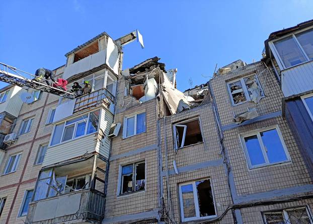 Rescuers evacuate a woman from a residential building damaged by an airstrike in Kharkiv
