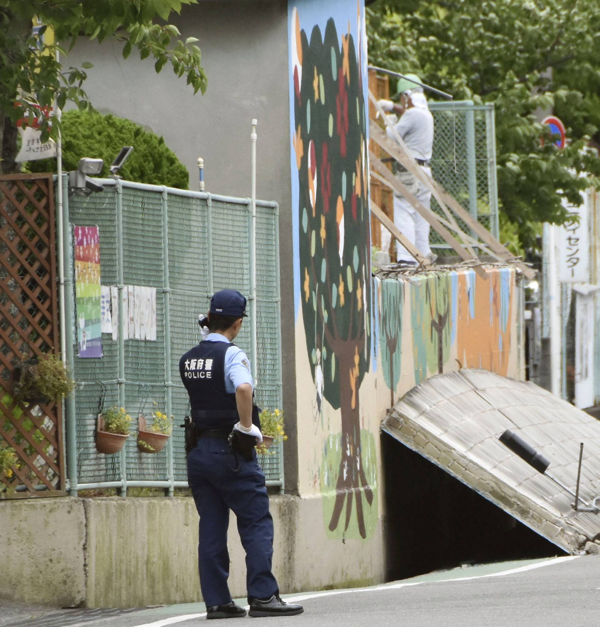 A police officer stand guard at the site where a girl was killed by fallen wall caused by an earthquake at an elementary school in Takatsuki