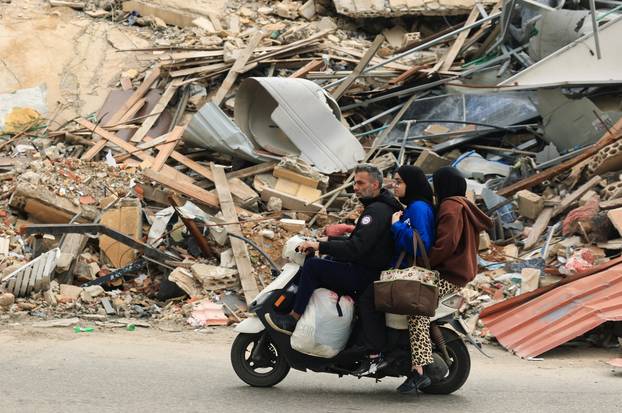 People ride past a damaged building, after a 10-day ceasefire between Lebanon and Israel went into effect, in the southern suburbs of Beirut