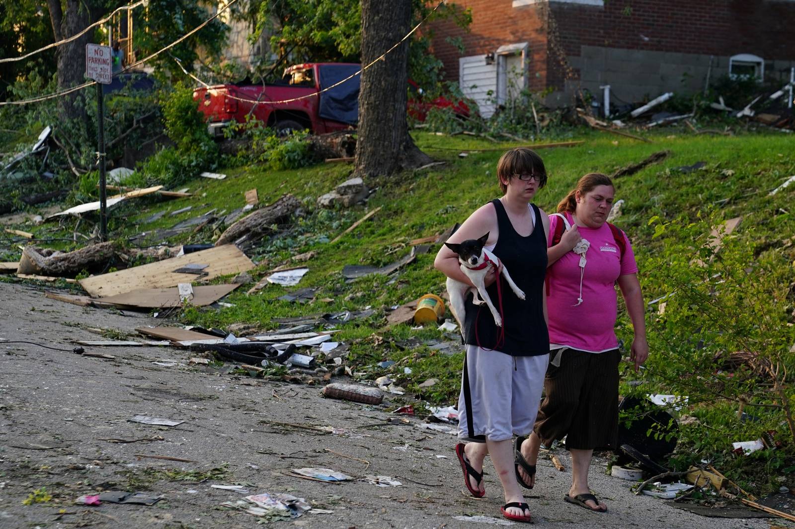 People walk along a road in front of a home following a tornado in Jefferson City