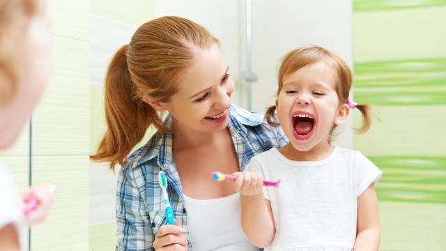 happy family mother and child girl cleans teeth with toothbrush