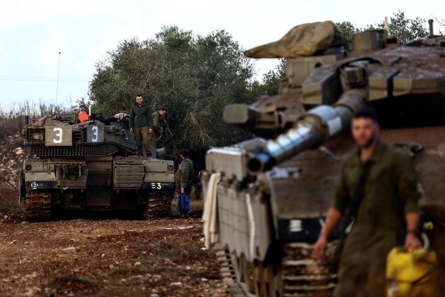 Israeli soldiers stand by their tanks near Israel's border with Lebanon in northern Israel
