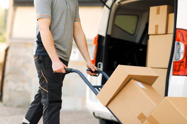 Professional,Delivery,Guy,Pushing,A,Hand,Truck,Loaded,With,Packages,