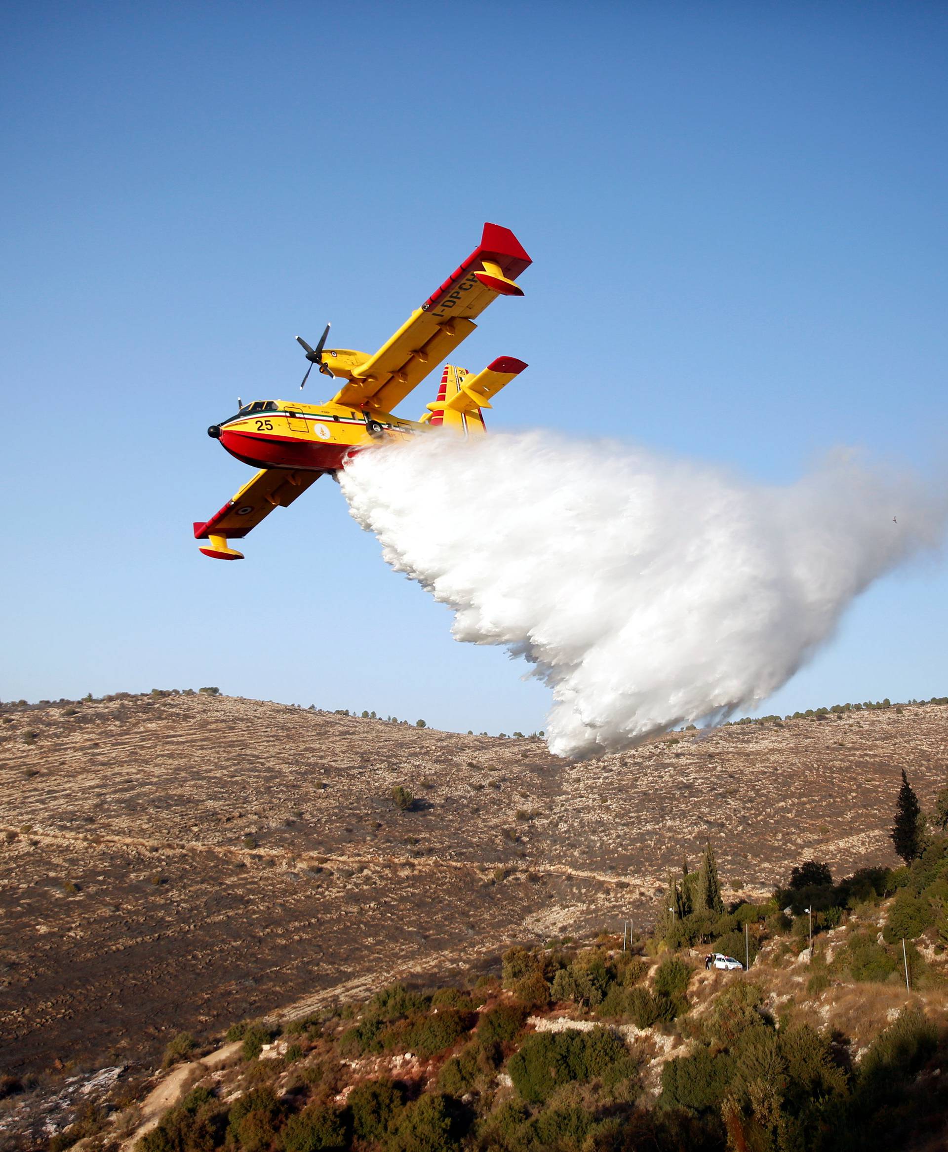 A foreign firefighting plane drops fire retardant during a wildfire, around the communal settlement of Nataf, close to Jerusalem