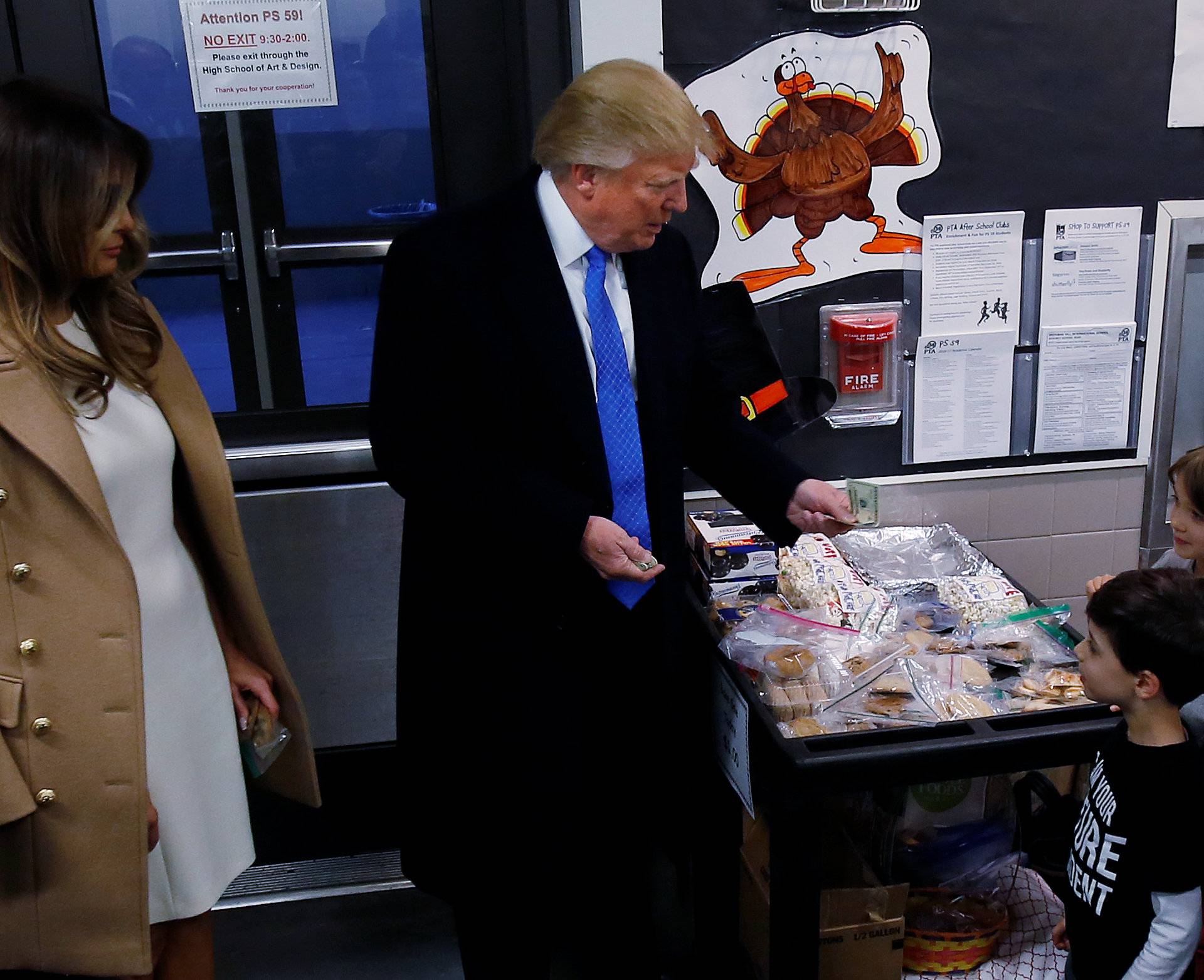 Republican presidential nominee Donald Trump hands money to a child at a bake sale table before voting at PS 59 in New York