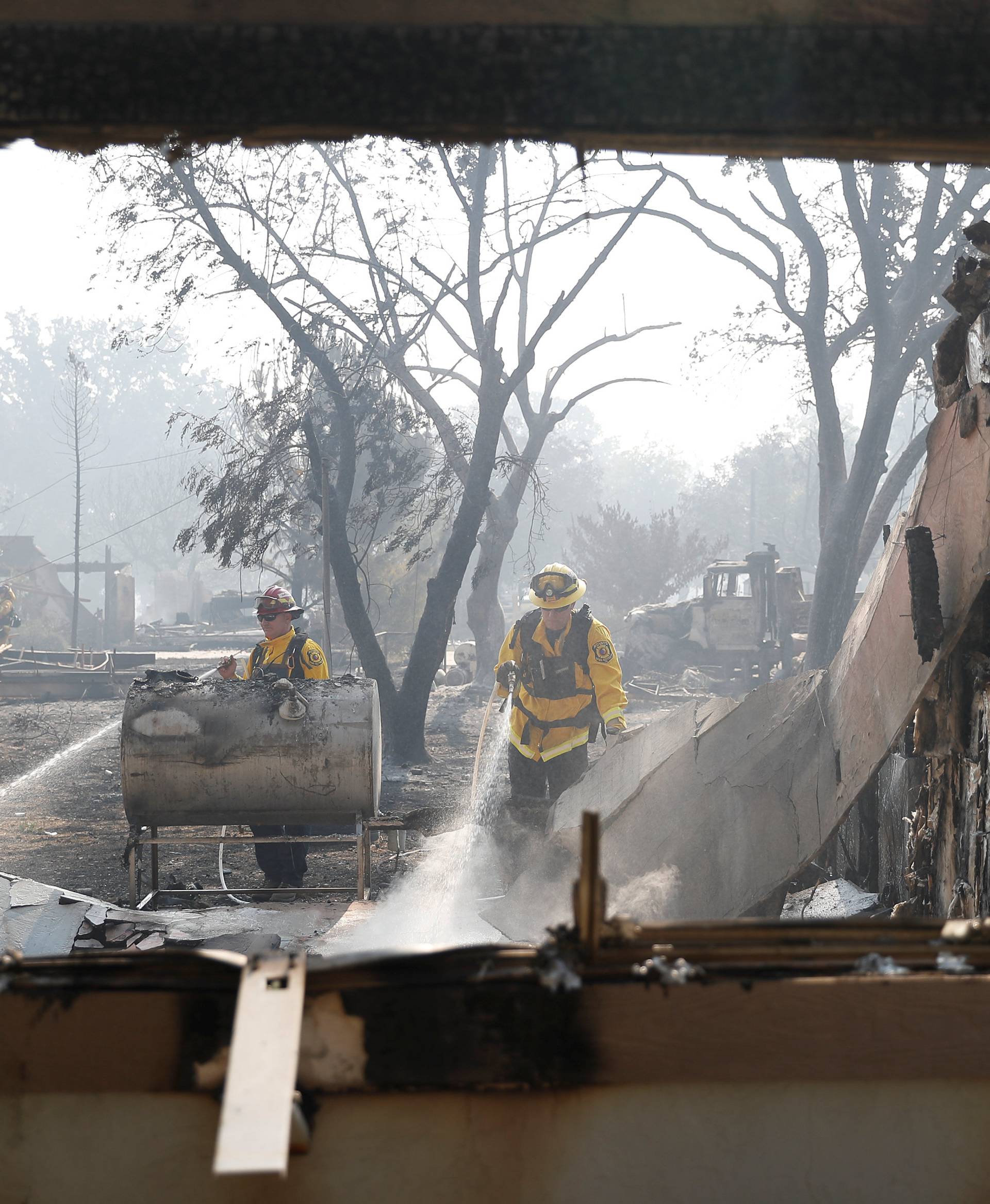 Firefighters spray water into a damaged building while battling the Clayton Fire at Lower Lake in California