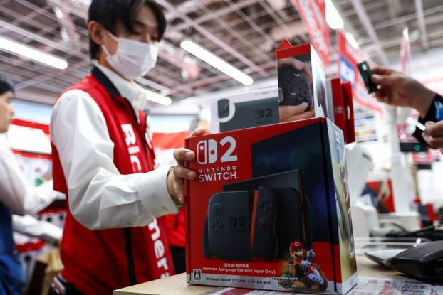 A staff member holds a Nintendo Switch 2 game console as Nintendo starts selling the new consoles globally, at an electronics store in Tokyo