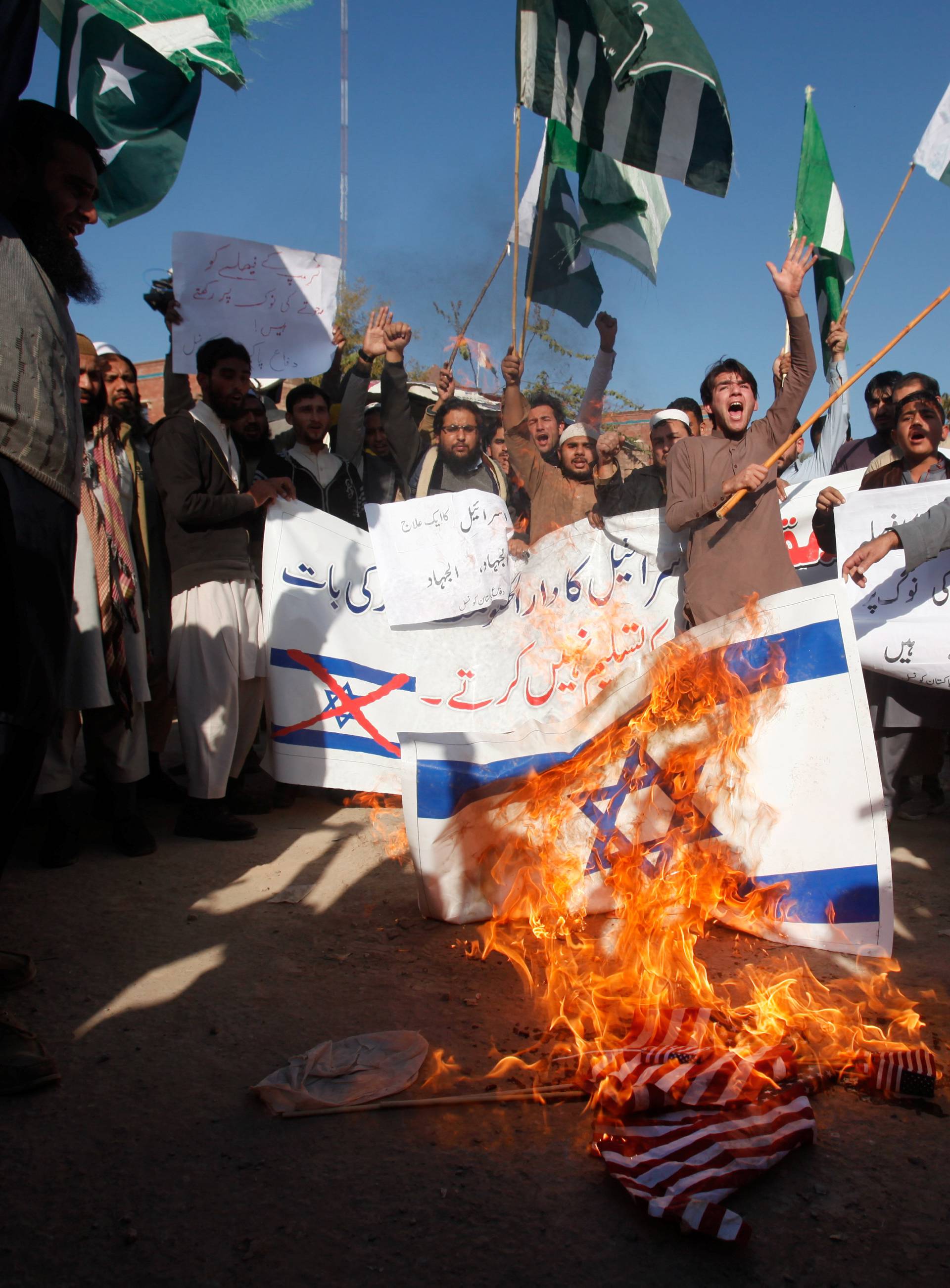 Supporters of the Difa-e-Pakistan Council burn Israeli and US flags during protest against U.S. President Trump's decision to recognize Jerusalem as the capital of Israel