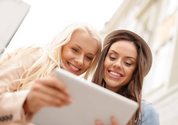 two beautiful girls looking into tablet pc