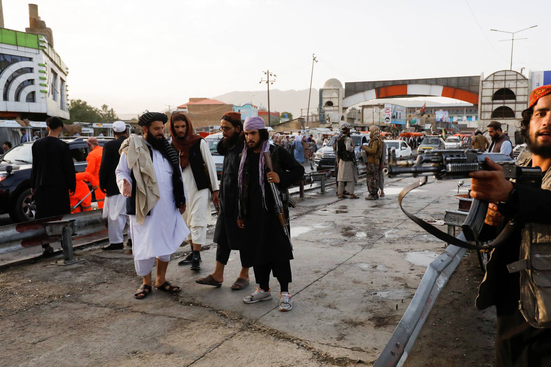 Taliban fighters stand guard at the site of a blast in Kabul