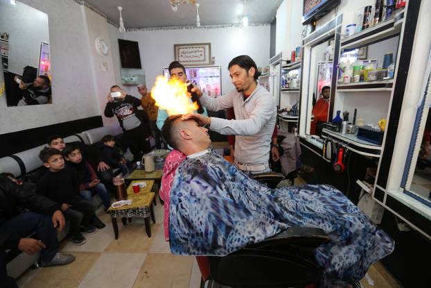 Palestinian barber Ramadan Odwan styles and straightens the hair of a customer with fire at his salon in Rafah, in the southern Gaza Strip