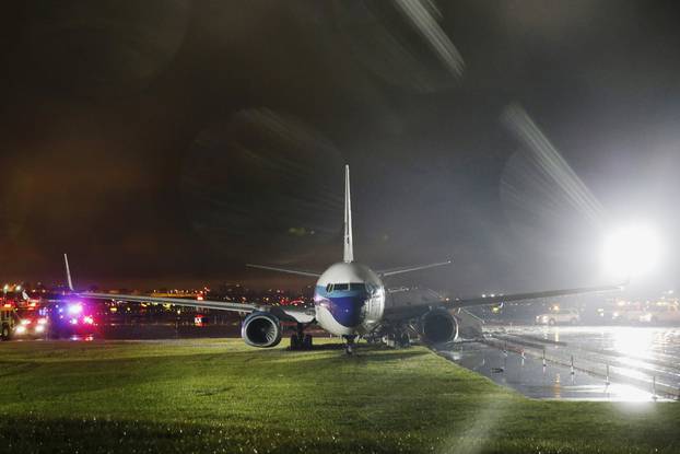 A campaign plane that had been carrying Mike Pence rests in the grass after it skidded off the runway while landing in the rain at LaGuardia Airport in New York