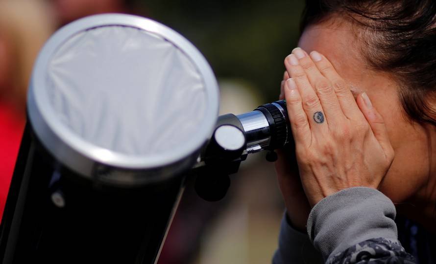 A woman uses a telescope to observe the planet Mercury transit in front of the sun outside Buenos Aires' planetarium