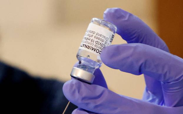 FILE PHOTO: A medical volunteer prepares a syringe containing a dose of Comirnaty