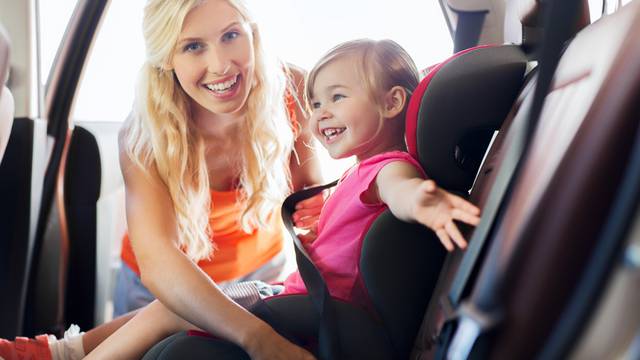 happy mother fastening child with car seat belt
