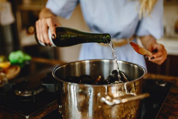 Girl,Adding,White,Wine,To,A,Pan,With,Mussels,,Woman