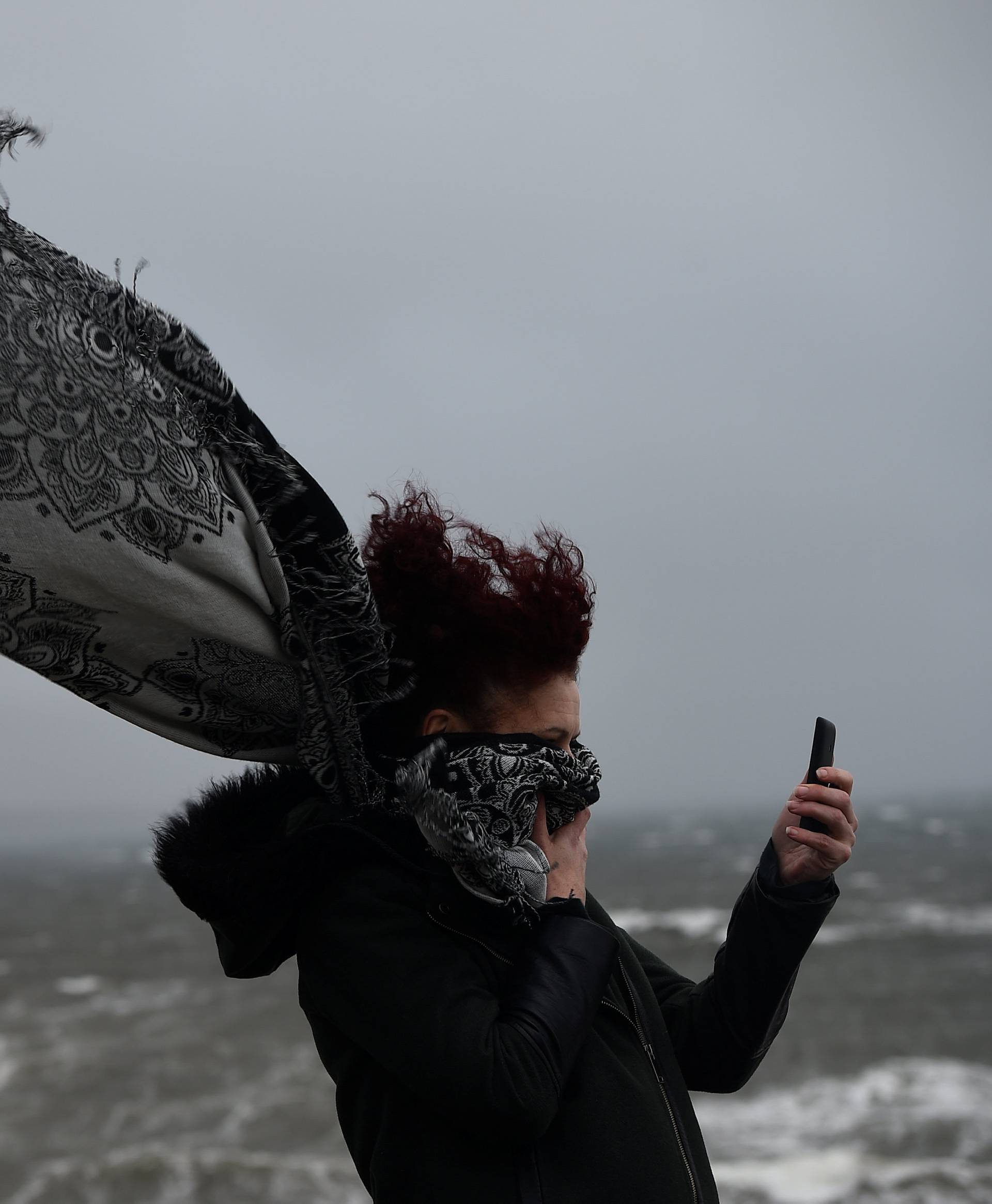 A woman takes a picture during storm Ophelia in the County Clare town of Lahinch