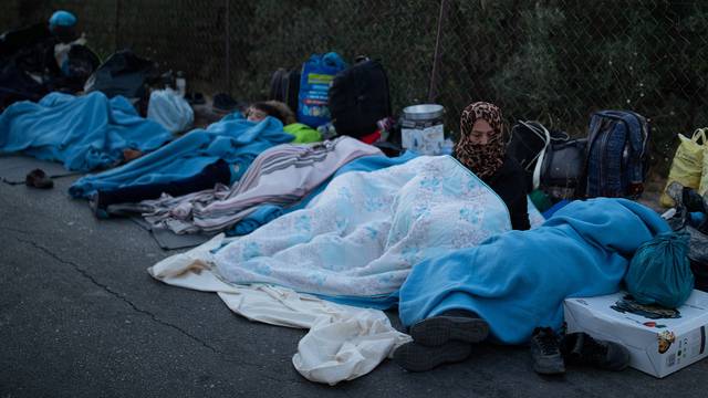 Refugees and migrants sleep on a road following a fire at the Moria camp on the island of Lesbos