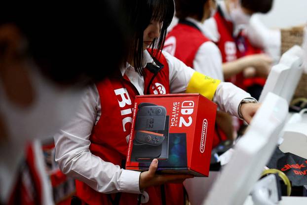 A member of staff holds Nintendo Switch 2 game console as Nintendo starts selling the new consoles globally, at an electronics store in Tokyo