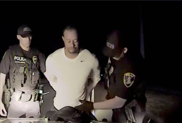 Tiger Woods is seen handcuffed and searched by police officers in this still image from police dashcam video in Jupiter